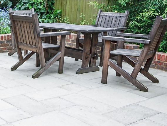A paved patio with outdoor wooden table and chairs surrounded by planting