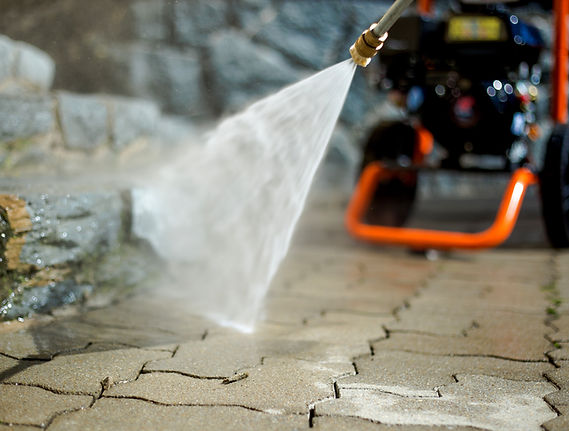 A pressure washer spraying water across paving stones